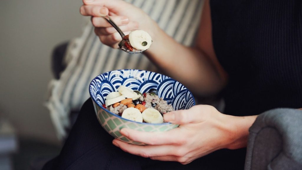 person holding spoon and bowl of food
